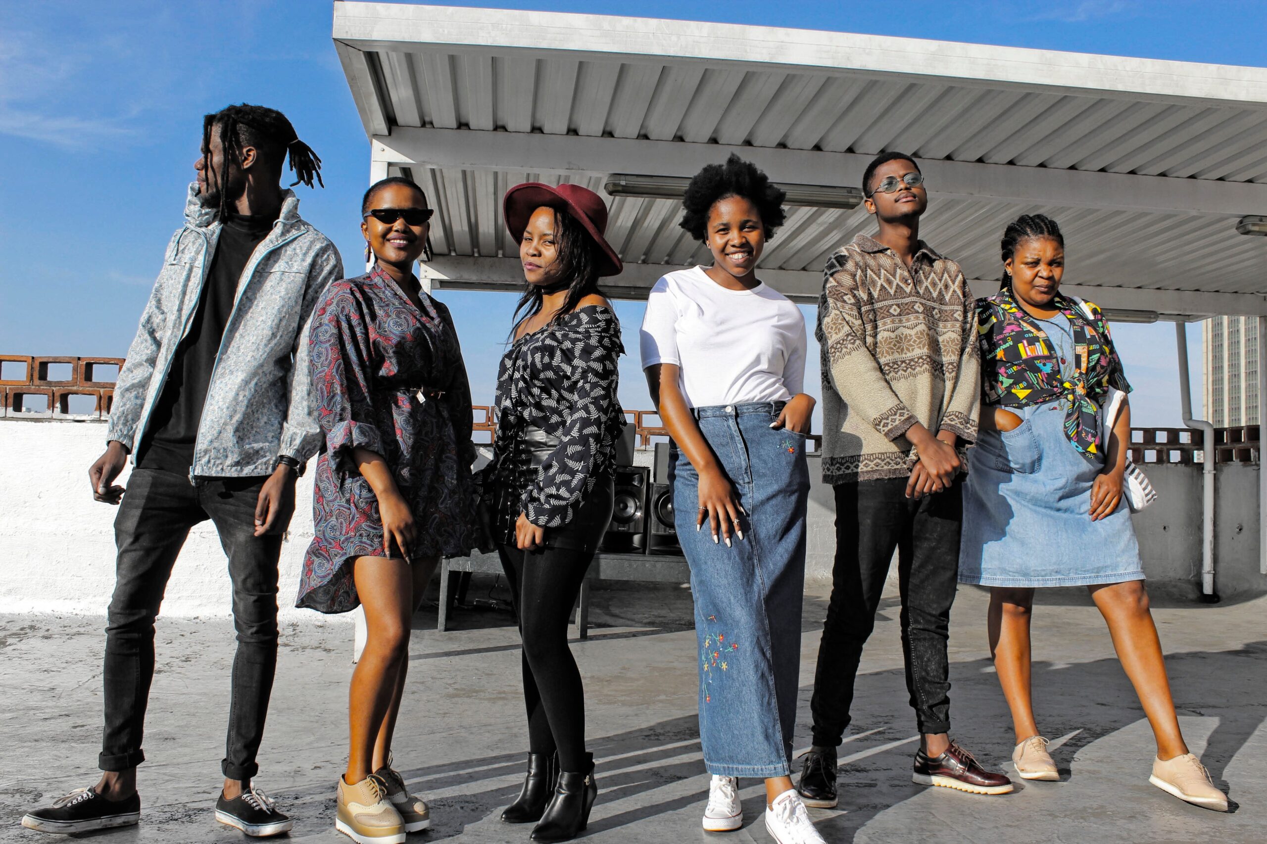 About Stylish young adults in diverse fashion posing together on a rooftop under a sunny sky.
